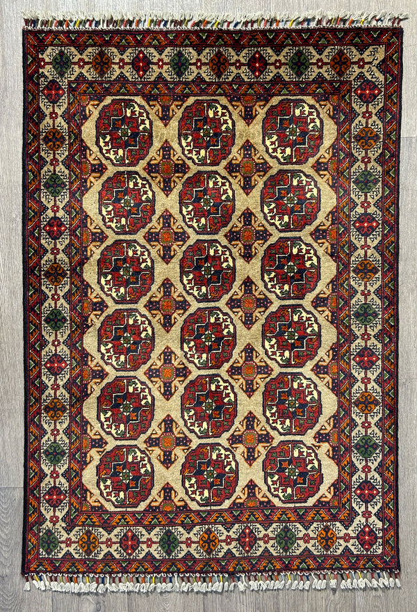 Authentic Handknotted Beige Afghan Kundus Wool Rug 139cm x 96cm
Traditional elephant foot gul motifs in multiple veg dyed colours including red blue and orange.  The rug has a heraldic feel to it.The rug features a soft background in a natural shade of sheep's wool