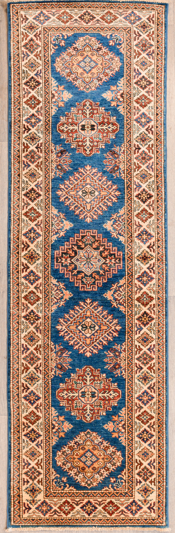 Authentic Hand Woven Blue Afghan Super Kazak Wool Runner 256cm x 77cm
Beautiful blue &amp; cream tones all over made from local vegetable &amp; plant dyes

Woven Using Premium Quality Wool gives an Unrivallled Shine Off the Pile
Originating from the Caucaus Region, the Kazak Design is now Mastered by the Generational Weavers of North-Central Asia
