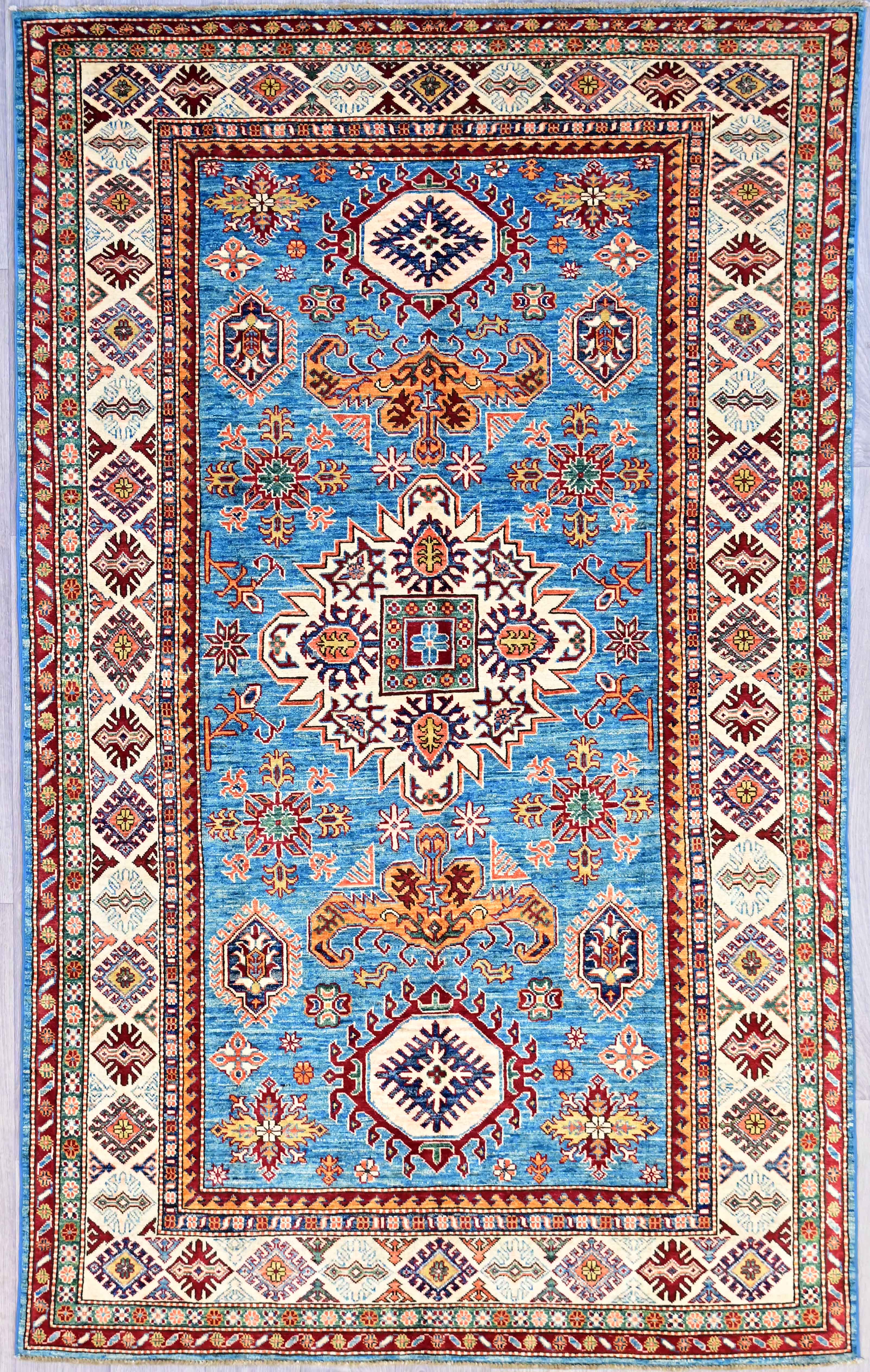 Authentic Blue Fine Afghan Super Kazak Wool Rug 286cm x 173cm
Attractive bright marled Turquoise field showing of magnificent Aztec style, finely woven, detailed medallions. "Super" refers both to the qualiity of the weave and the superior quality of the silky wool which has a wonderful natural sheen