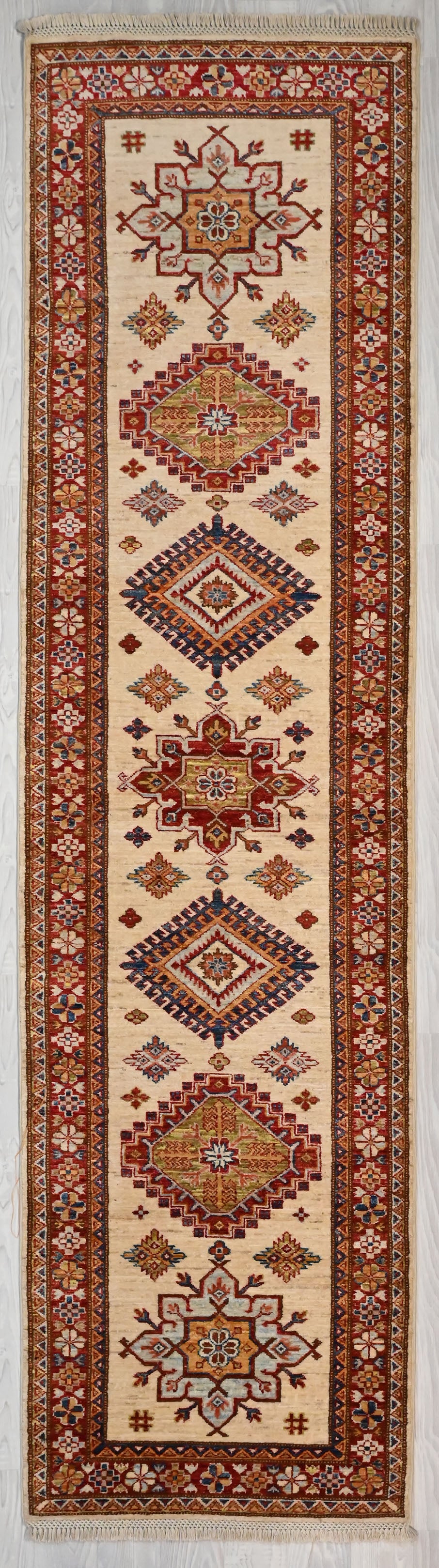 Authentic Handknotted Cream Afghan Super Kazak Wool Runner 308cm x 78cm
"Aztec" style Design Super Kazak runner with multicolour tones all over made from local vegetable &amp; plant dyes
Woven Using Premium Quality Wool gives an unrivallled sheen to the pile