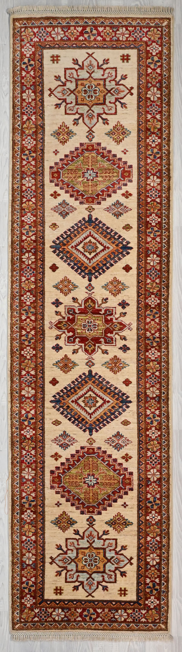 Authentic Handknotted Cream Afghan Super Kazak Wool Runner 308cm x 78cm
"Aztec" style Design Super Kazak runner with multicolour tones all over made from local vegetable &amp; plant dyes
Woven Using Premium Quality Wool gives an unrivallled sheen to the pile