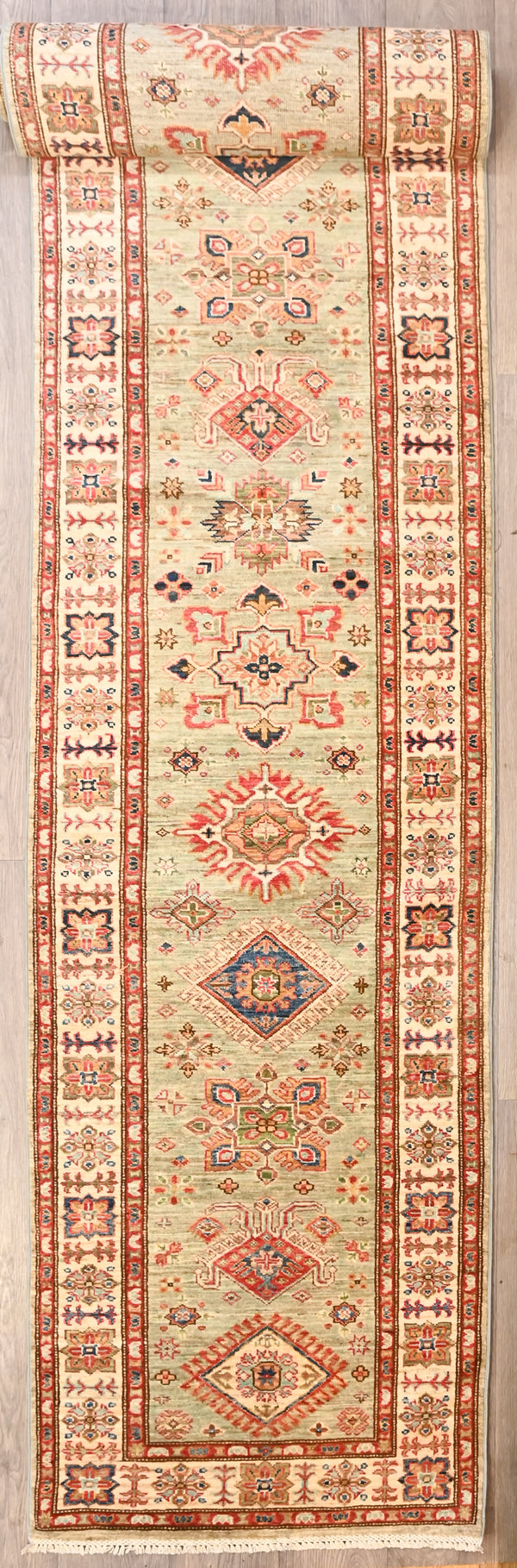 Authentic Hand Woven Fine Olive Green Afghan Super Kazak Wool Runner 629cm x 82cm
Beautiful light green centre tones all made from natural veg dyes
Truly a one of a kind hallway runner unique in its size and design

Woven Using Premium Quality Wool gives an Unrivallled Shine Off the Pile