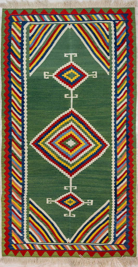 Authentic Handknotted Green Persian Wool Kilim 185cm x 125cm
Bold multicolour tribal design woven from memory. Archaic rams horn motifs on the corners of the diamonds stand out in cream. Unusual rare green background made with natural dyes such as indigo and weld. Red colours made with madder root.
Suits Boho, modern or MCM interiors. Suits galley kitchen

Durable and Wear Resistant Suitable for High Traffic Areas
