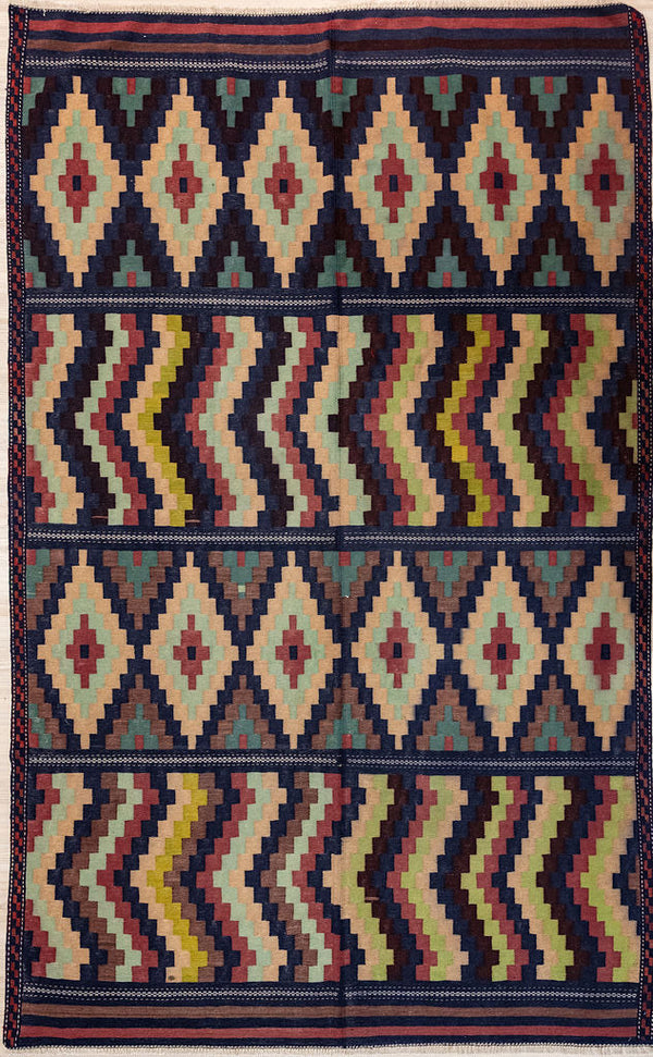 Authentic Handknotted Multicolour Vintage Persian Wool Kilim 288cm x 185cm. In harmonising earthy tons of brown and, yellow pale indigo and pale green This one off design rug has real impact and a North African or Micronesian feel
Colour tones have aged gracefully over the decades and the wool has softened. Fringes are short and practical.Kilim are a light flat weave reversible rug used for over a millennium by the nomadic tribes of Central Asia. These portable rugs can  go with you on travels or picnics.